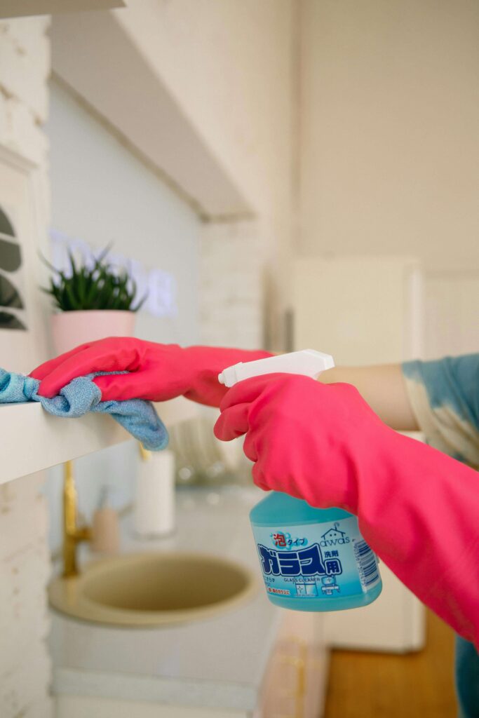 Person dusting a shelf with a microfiber cloth - Caribbean Cleaning Srq